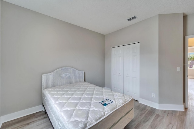 bedroom featuring a closet, hardwood / wood-style flooring, and a textured ceiling