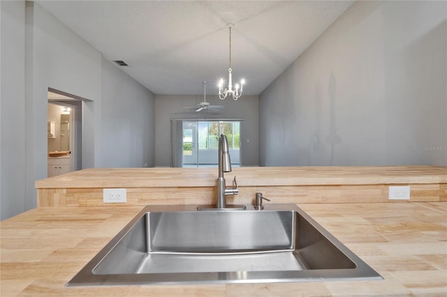 kitchen with a notable chandelier, a textured ceiling, sink, decorative light fixtures, and wood counters