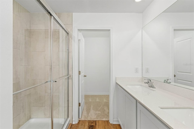 bathroom featuring walk in shower, wood-type flooring, and double sink vanity