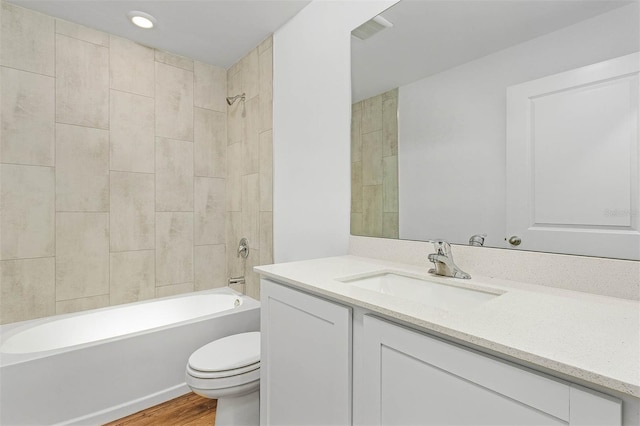 full bathroom with tiled shower / bath, toilet, vanity, and hardwood / wood-style flooring