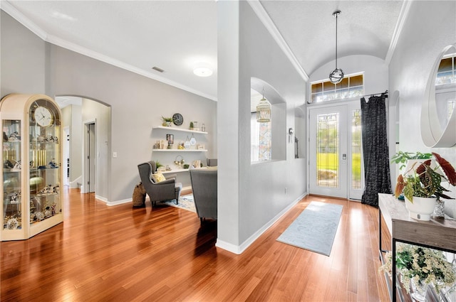 foyer with crown molding, lofted ceiling, and light hardwood / wood-style flooring