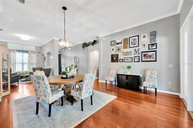 dining space featuring light hardwood / wood-style flooring, a notable chandelier, and ornamental molding