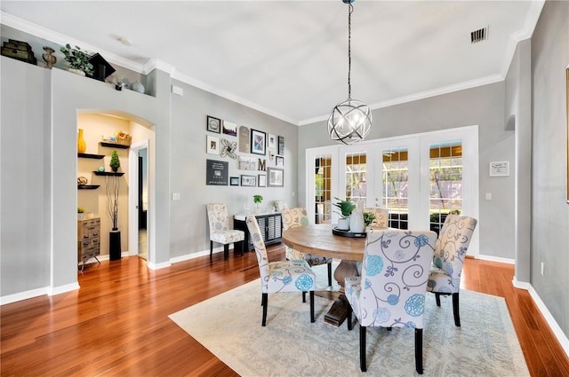 dining area with an inviting chandelier, ornamental molding, and light hardwood / wood-style flooring