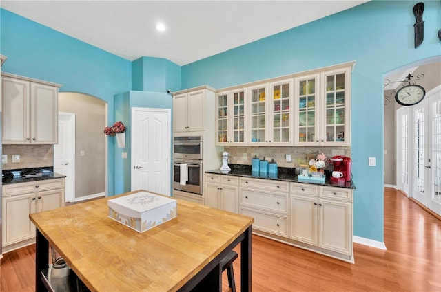 kitchen with light hardwood / wood-style floors, backsplash, and double oven