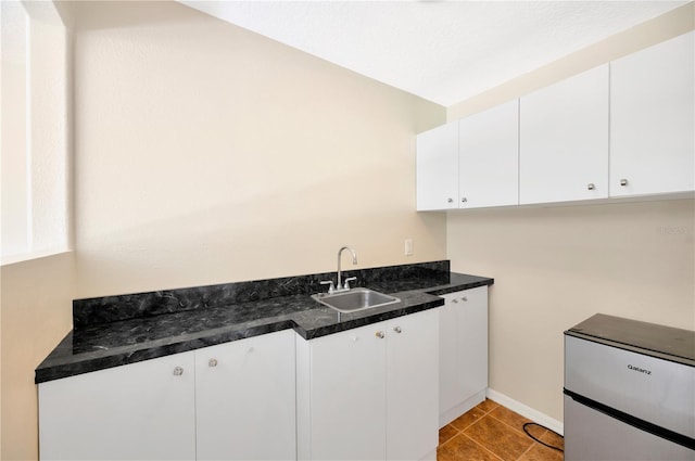 kitchen with white cabinets, sink, and light tile flooring