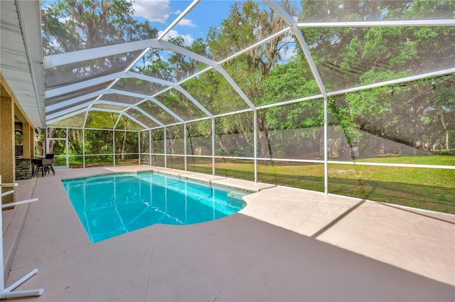 view of pool with a lawn, a patio area, and glass enclosure