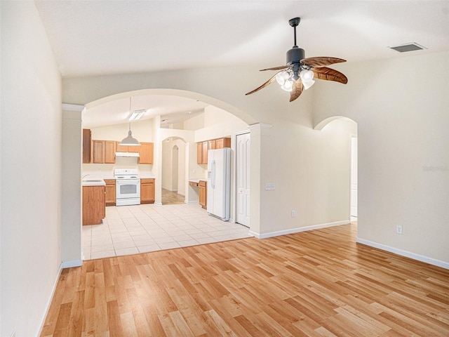 unfurnished living room featuring light wood-type flooring, visible vents, vaulted ceiling, and a ceiling fan