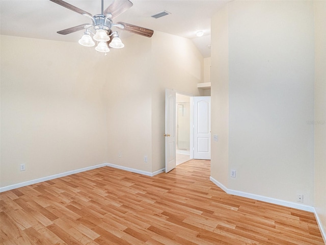 spare room featuring high vaulted ceiling, light wood finished floors, visible vents, and baseboards