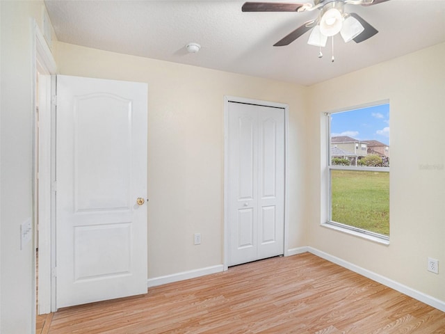 unfurnished bedroom with ceiling fan, a closet, and light hardwood / wood-style floors