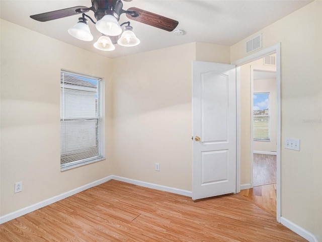 empty room with a ceiling fan, light wood-style flooring, visible vents, and baseboards