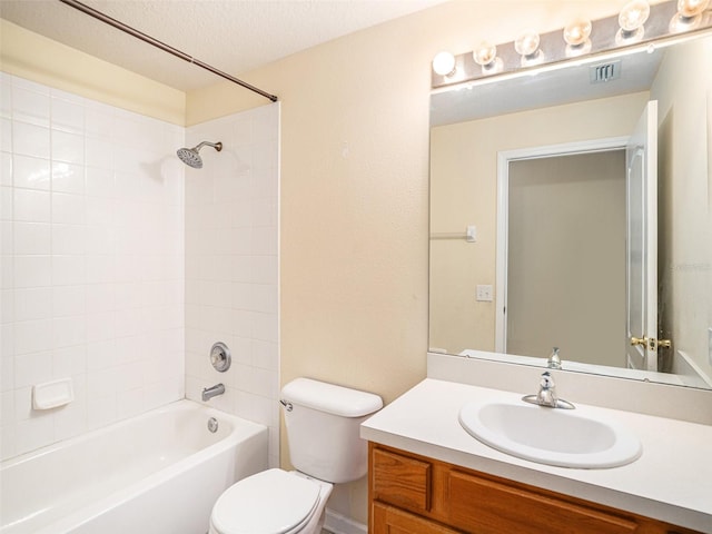 full bathroom featuring a textured ceiling, vanity, tiled shower / bath, and toilet