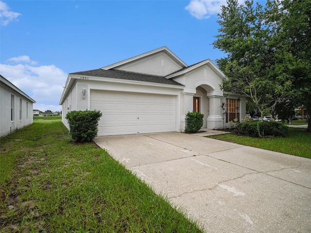 single story home featuring a garage, a shingled roof, concrete driveway, a front lawn, and stucco siding