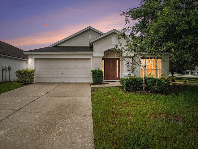 view of front facade with a garage, driveway, roof with shingles, stucco siding, and a front lawn