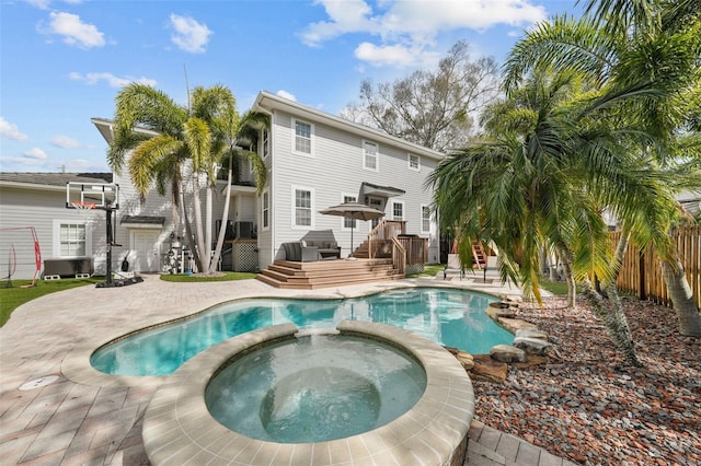 view of pool featuring an in ground hot tub, a patio area, and a wooden deck