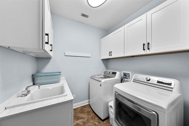 laundry room featuring washer and clothes dryer and cabinets