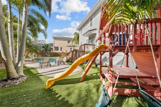 view of play area with a lawn, a pool side deck, and a patio