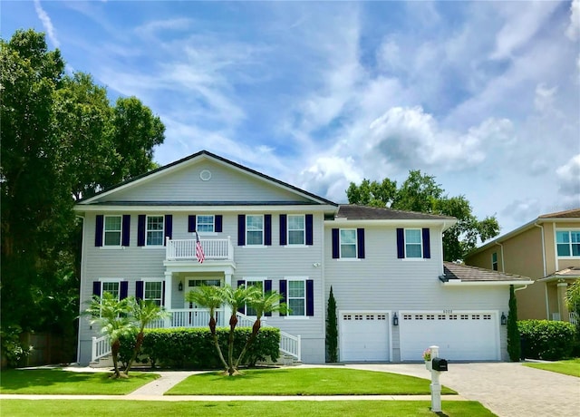 view of front facade with covered porch, a garage, a balcony, and a front lawn