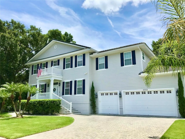 colonial inspired home featuring a garage, a balcony, and a front yard