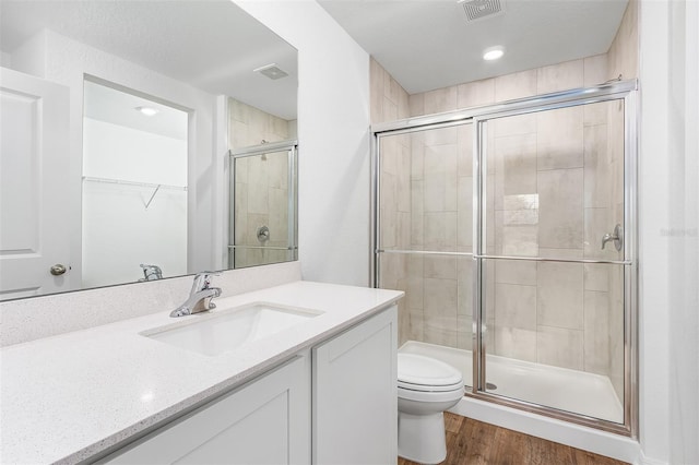 bathroom with vanity, toilet, hardwood / wood-style flooring, and walk in shower