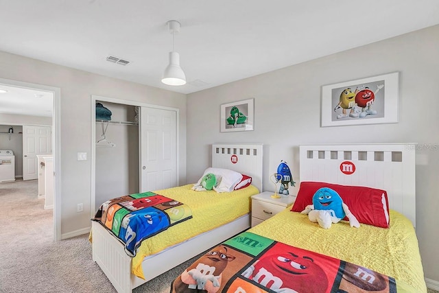 carpeted bedroom with washer / dryer and a closet