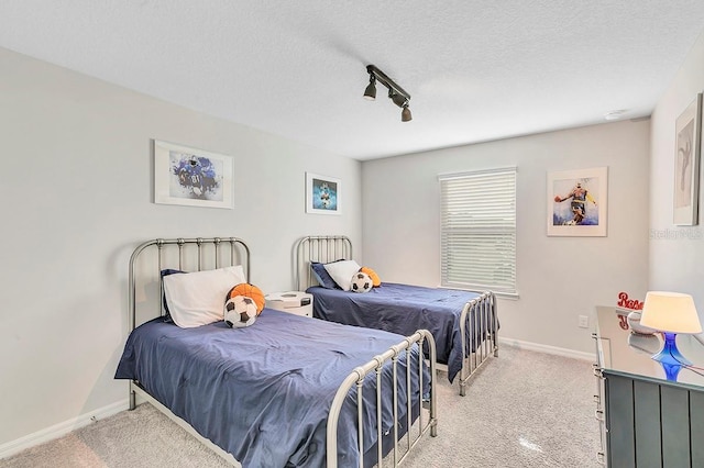 bedroom with a textured ceiling, light colored carpet, and track lighting