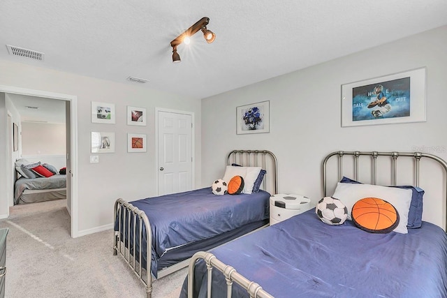 bedroom featuring light colored carpet and a textured ceiling