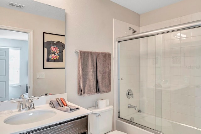 full bathroom with vanity, toilet, and enclosed tub / shower combo