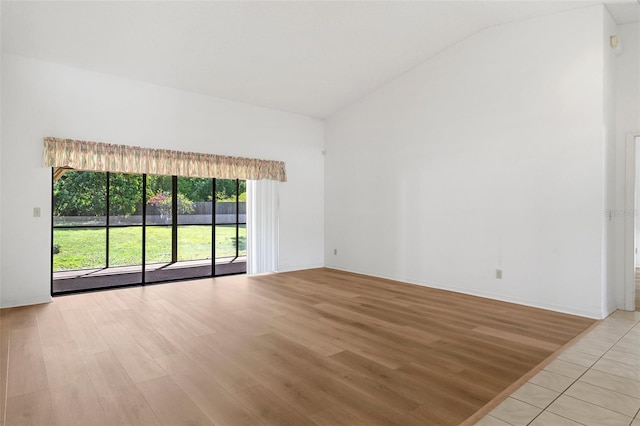 spare room featuring lofted ceiling and light tile floors