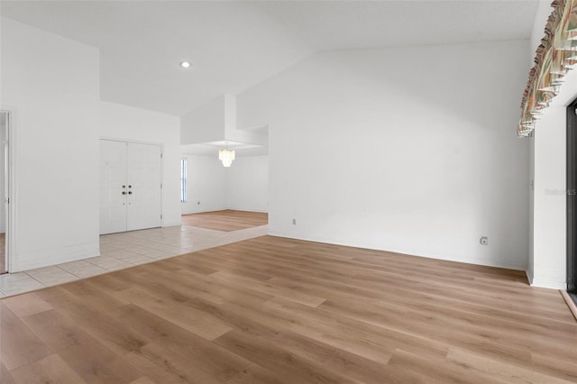 empty room featuring high vaulted ceiling and light wood-type flooring