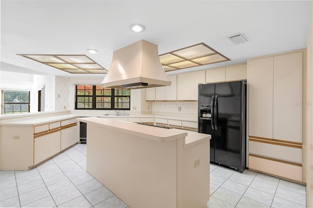 kitchen with a center island, light tile flooring, island range hood, black appliances, and kitchen peninsula