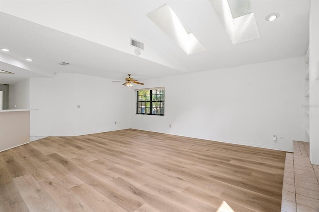 unfurnished room with light hardwood / wood-style flooring, ceiling fan, and vaulted ceiling with skylight