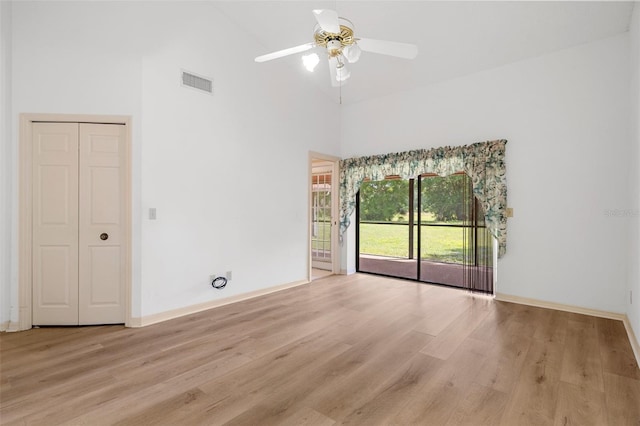 empty room featuring light hardwood / wood-style flooring, ceiling fan, and high vaulted ceiling