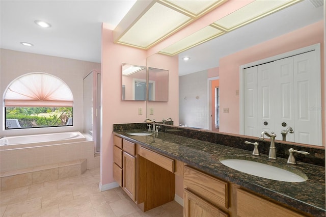 bathroom featuring tile floors, a relaxing tiled bath, and double vanity