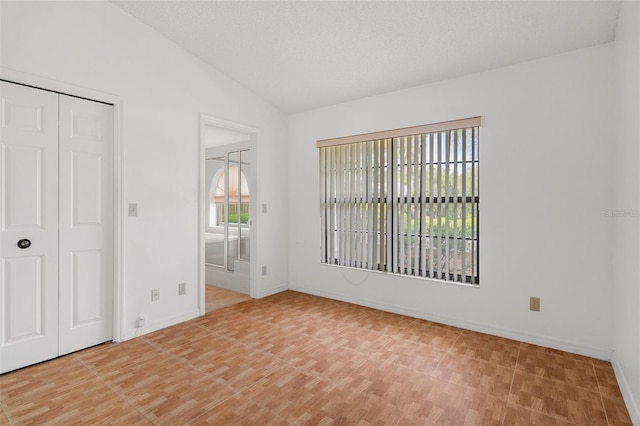 unfurnished bedroom with vaulted ceiling, multiple windows, and a closet