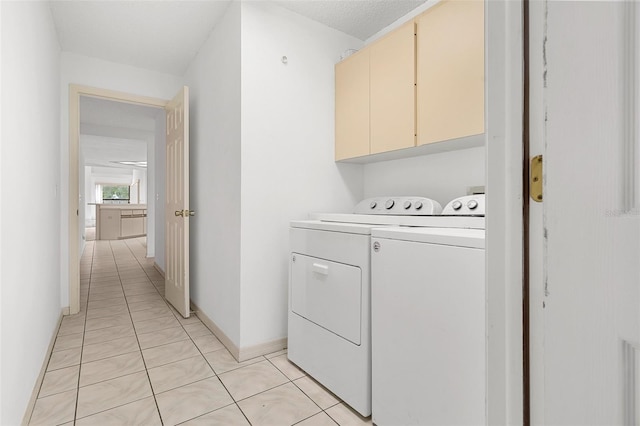 washroom featuring cabinets, washing machine and dryer, and light tile floors