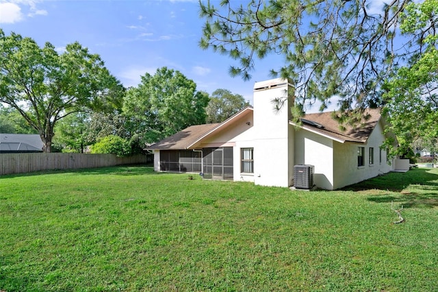 rear view of property featuring central AC unit, a yard, and a sunroom