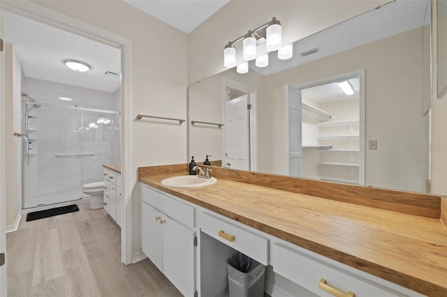 bathroom with a shower with door, wood-type flooring, toilet, and large vanity