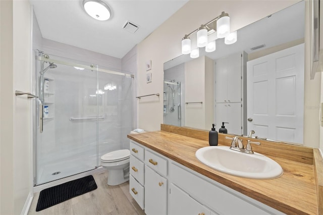 bathroom with hardwood / wood-style flooring, a shower with shower door, toilet, and vanity