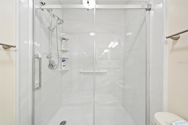 bathroom with a shower with shower door and toilet