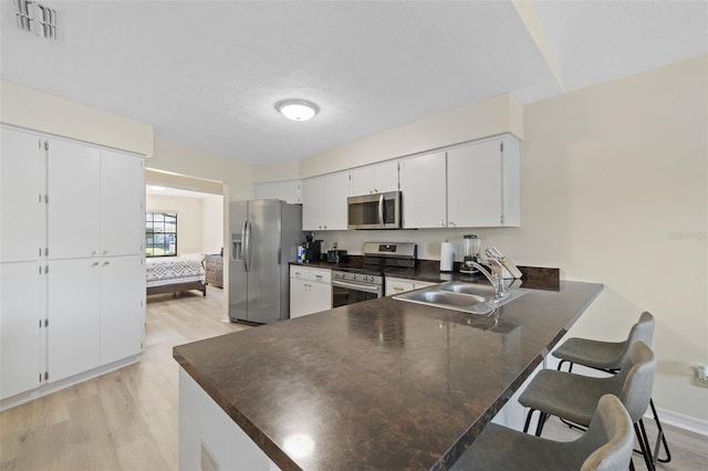 kitchen with white cabinets, light hardwood / wood-style flooring, sink, and stainless steel appliances