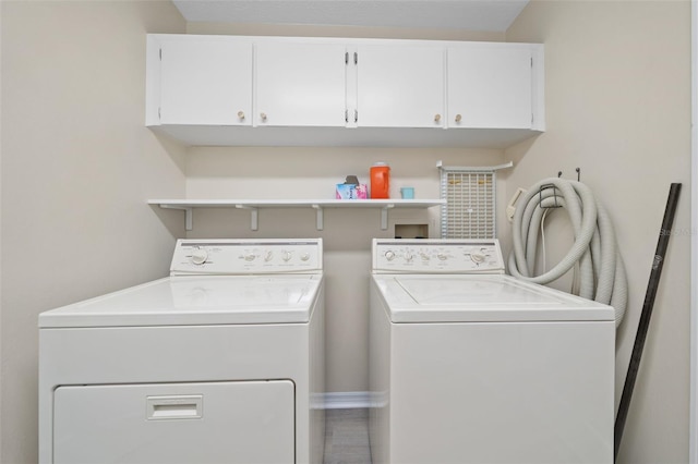 clothes washing area featuring cabinets, hookup for a washing machine, and separate washer and dryer