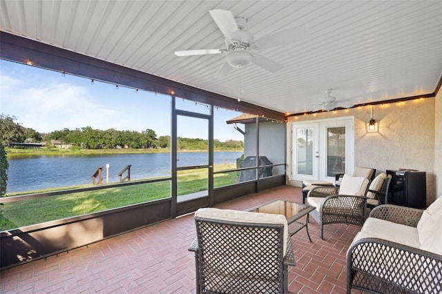 sunroom / solarium with ceiling fan, a water view, and french doors