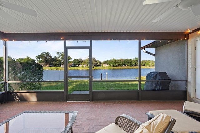 sunroom featuring ceiling fan and a water view