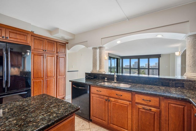 kitchen with dark stone counters, sink, decorative columns, and black appliances