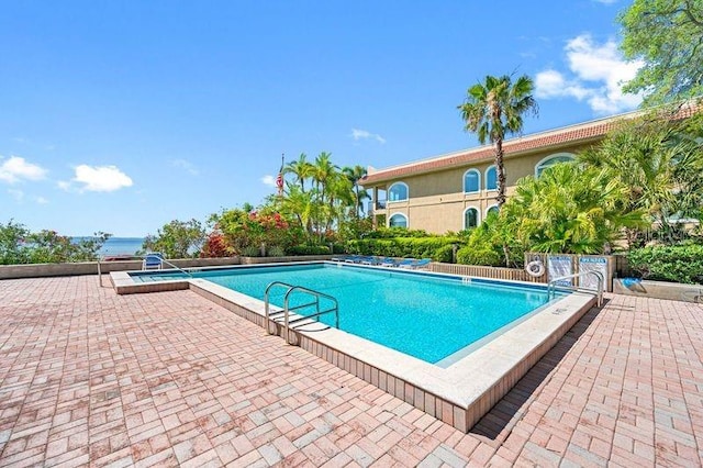 view of pool featuring a water view and a patio area