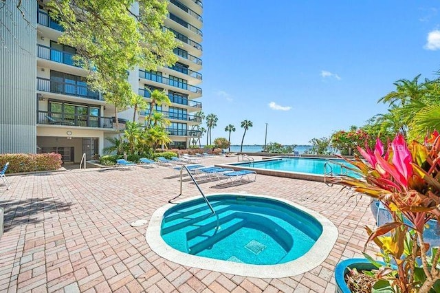 view of swimming pool with a hot tub and a patio area