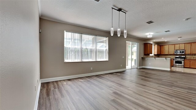 unfurnished living room with tile floors, a wealth of natural light, ornamental molding, and a textured ceiling