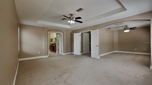 unfurnished room featuring light colored carpet, a tray ceiling, and ceiling fan