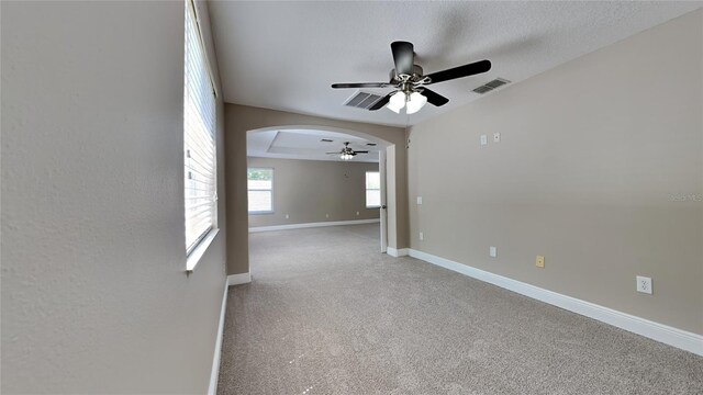 carpeted empty room with a raised ceiling and ceiling fan