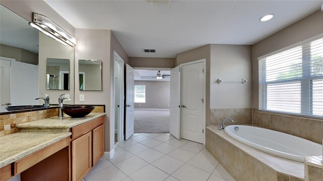 bathroom featuring tiled tub, tile floors, vanity, and ceiling fan